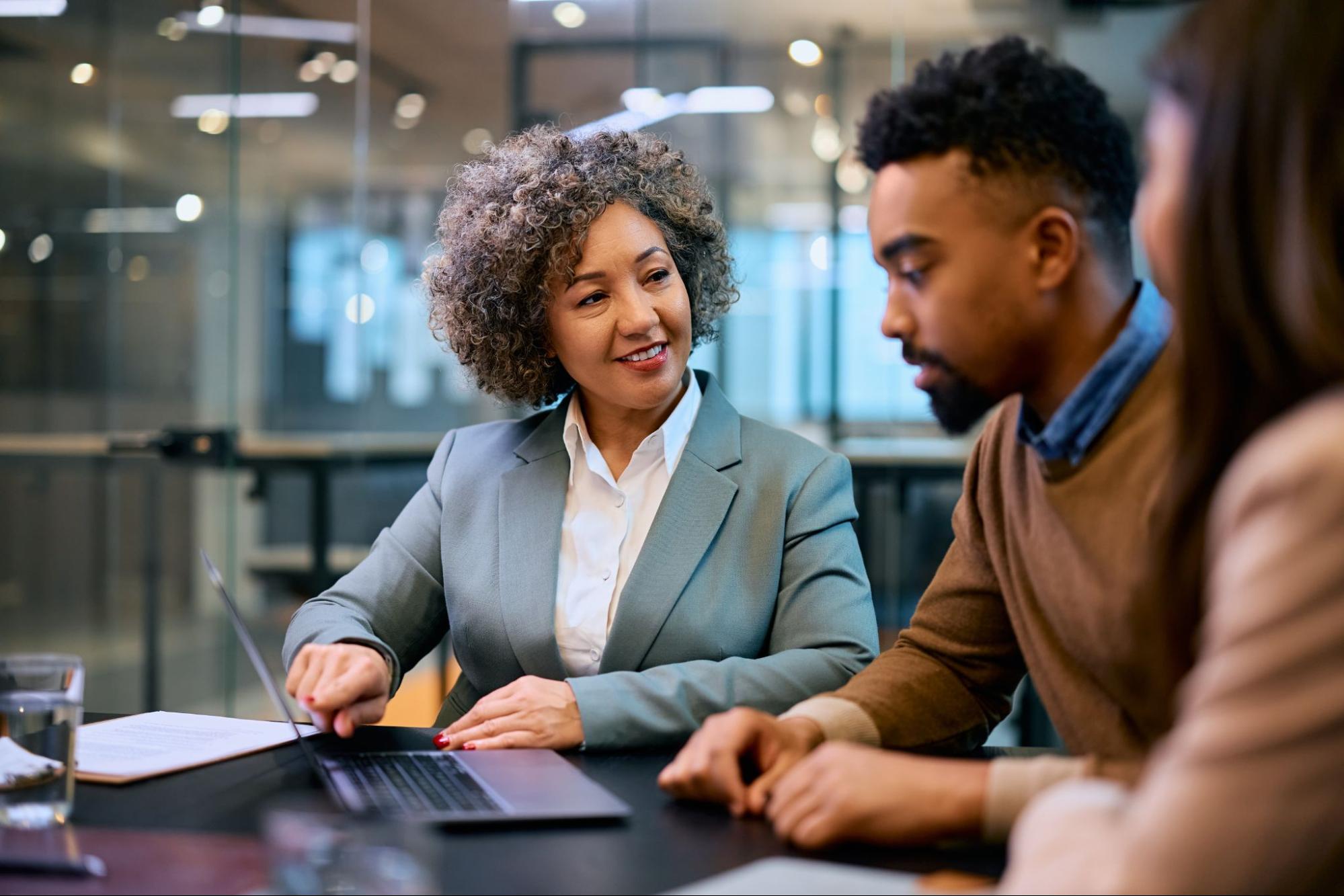 woman showing couple something on a laptop